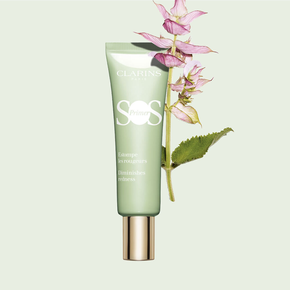 A tube of SOS Primer Green by Clarins to reduce the appearance of redness, with a branch of clary sage.