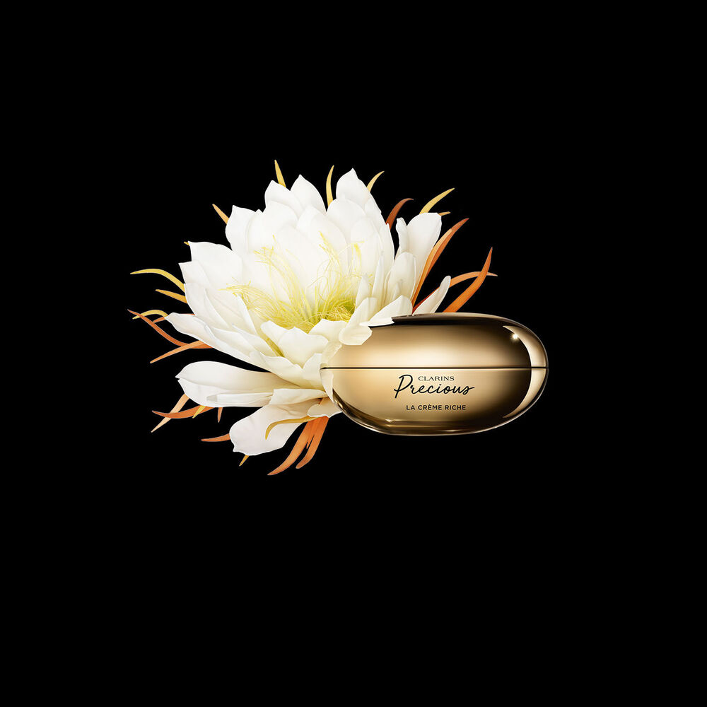 Packshot of Clarins Precious Rich Cream close to a Moonlight flower on dark background.