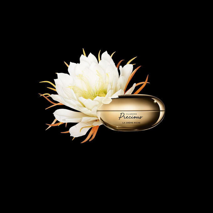 Packshot of Clarins Precious Rich Cream close to a Moonlight flower on dark background.