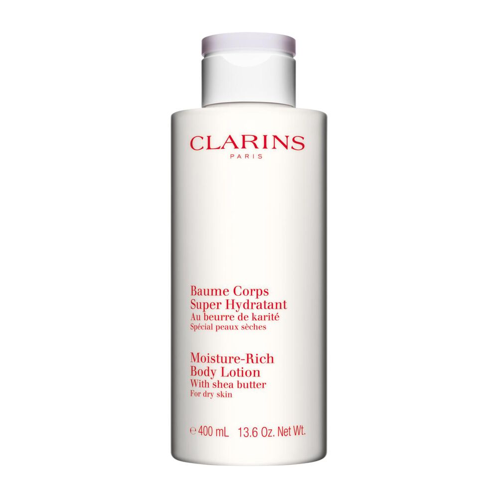 Bottle of Clarins Moisture-Rich Body Lotion close to some shea nuts on a white background.