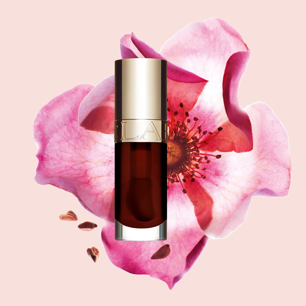 Packshot of Clarins Lip Comfort Oil Chocolate, placed next to a sweetbriar rose on a light pink background.
