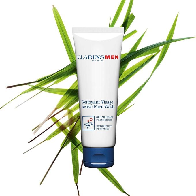 Packshot of the Active Face Wash, men's face cleanser by Clarins next to bison grass to emphasise its key ingredient.
