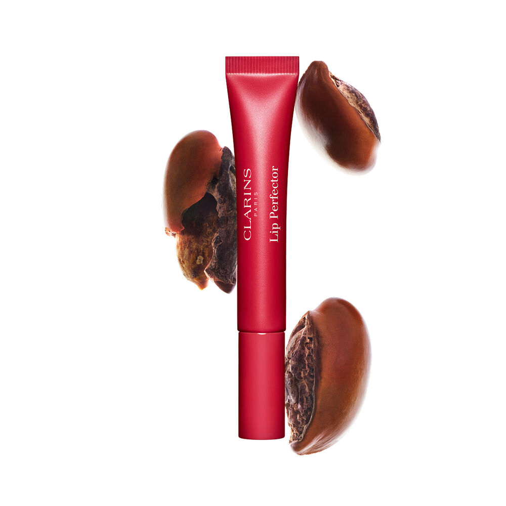 Plumping lip perfector tube shown with raw shea seeds to highlight the intense lip care formula for deep nourishment effect