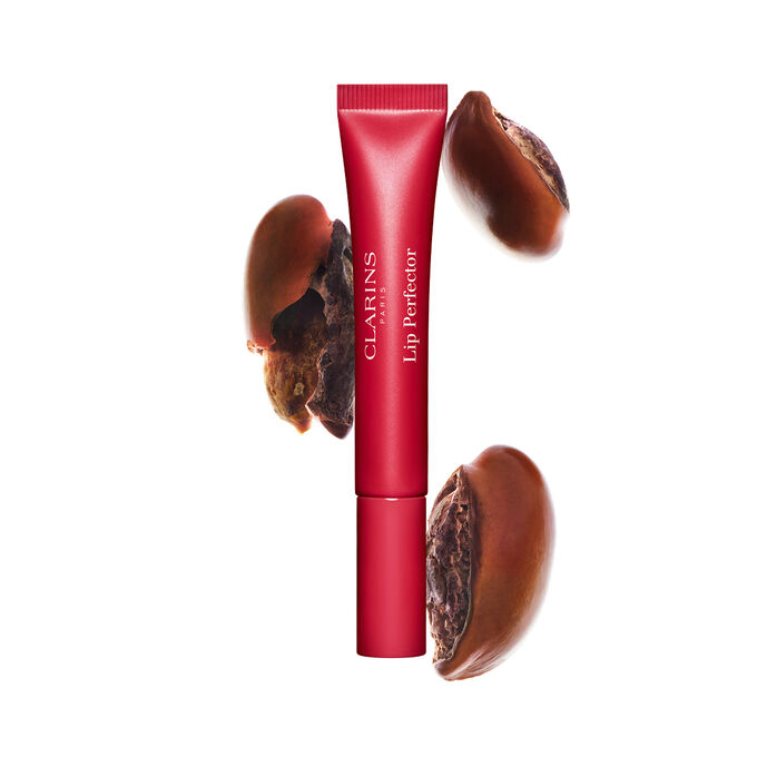 Plumping lip perfector tube shown with raw shea seeds to highlight the intense lip care formula for deep nourishment effect