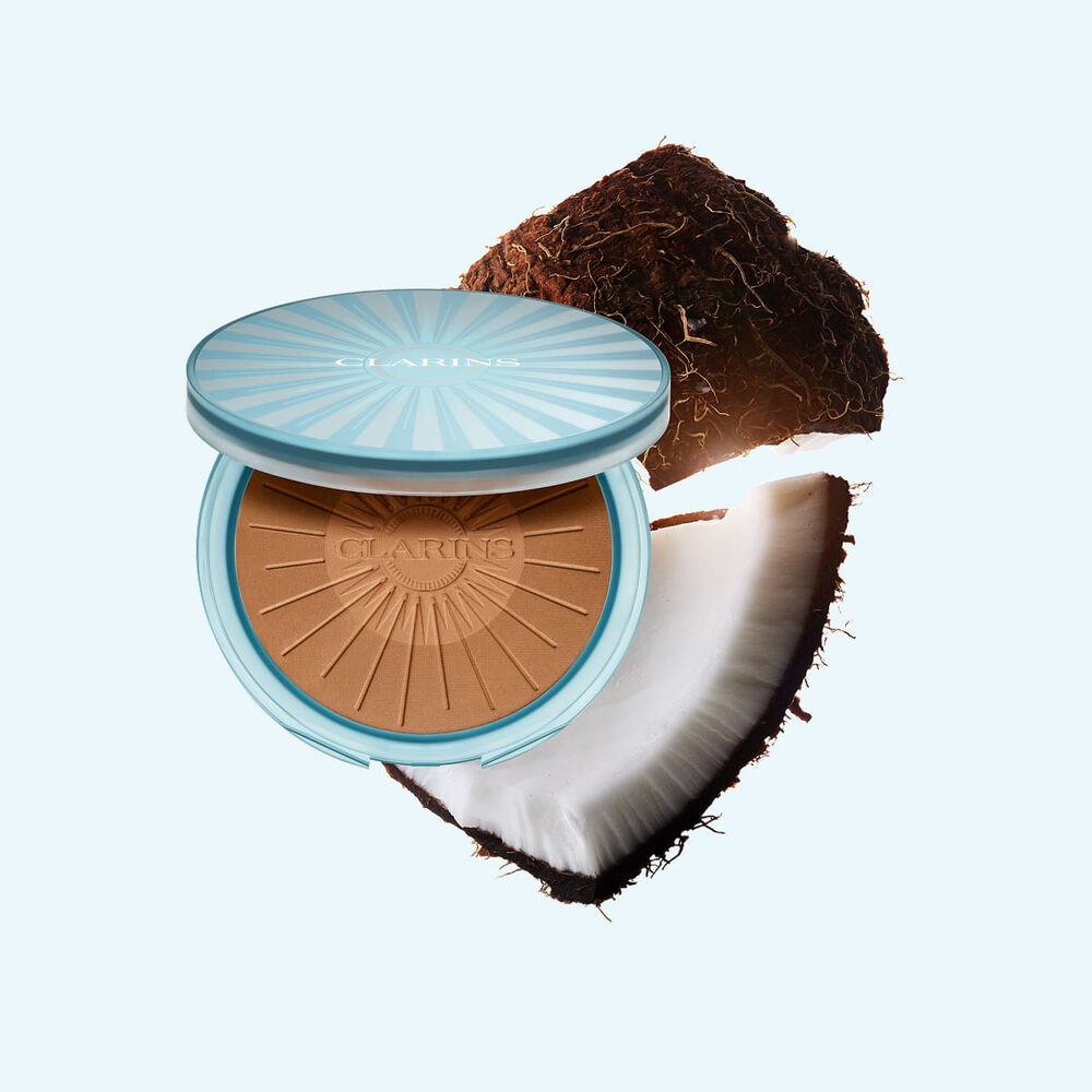 Packshot of Summer Bronzing Powder surrounded by coconut, illustrating its key ingredient for a natural, sun-kissed glow.