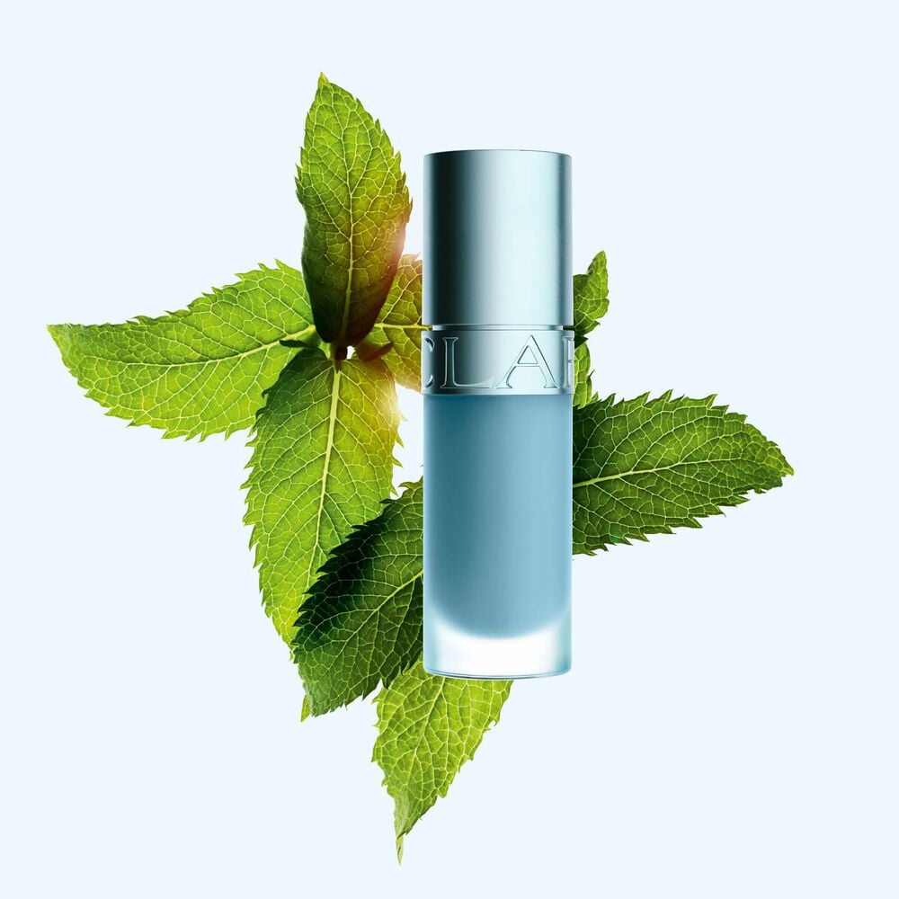 Packshot of Clarins Lip Comfort Oil with new cooling effect and glossy finish, in front of mint to highlight its key ingredient