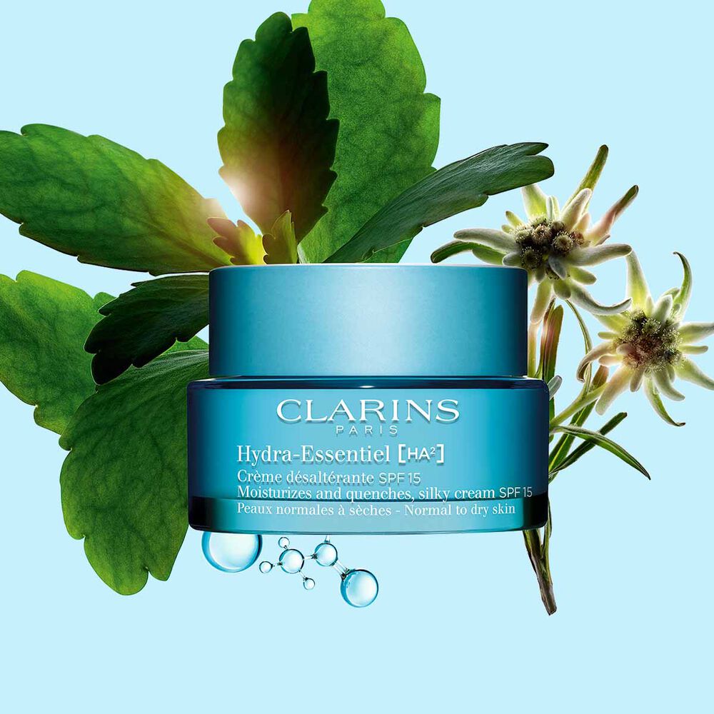 Packshot of Clarins Hydra-Essentiel SPF15 close to some edelweiss flowers on a blue background.