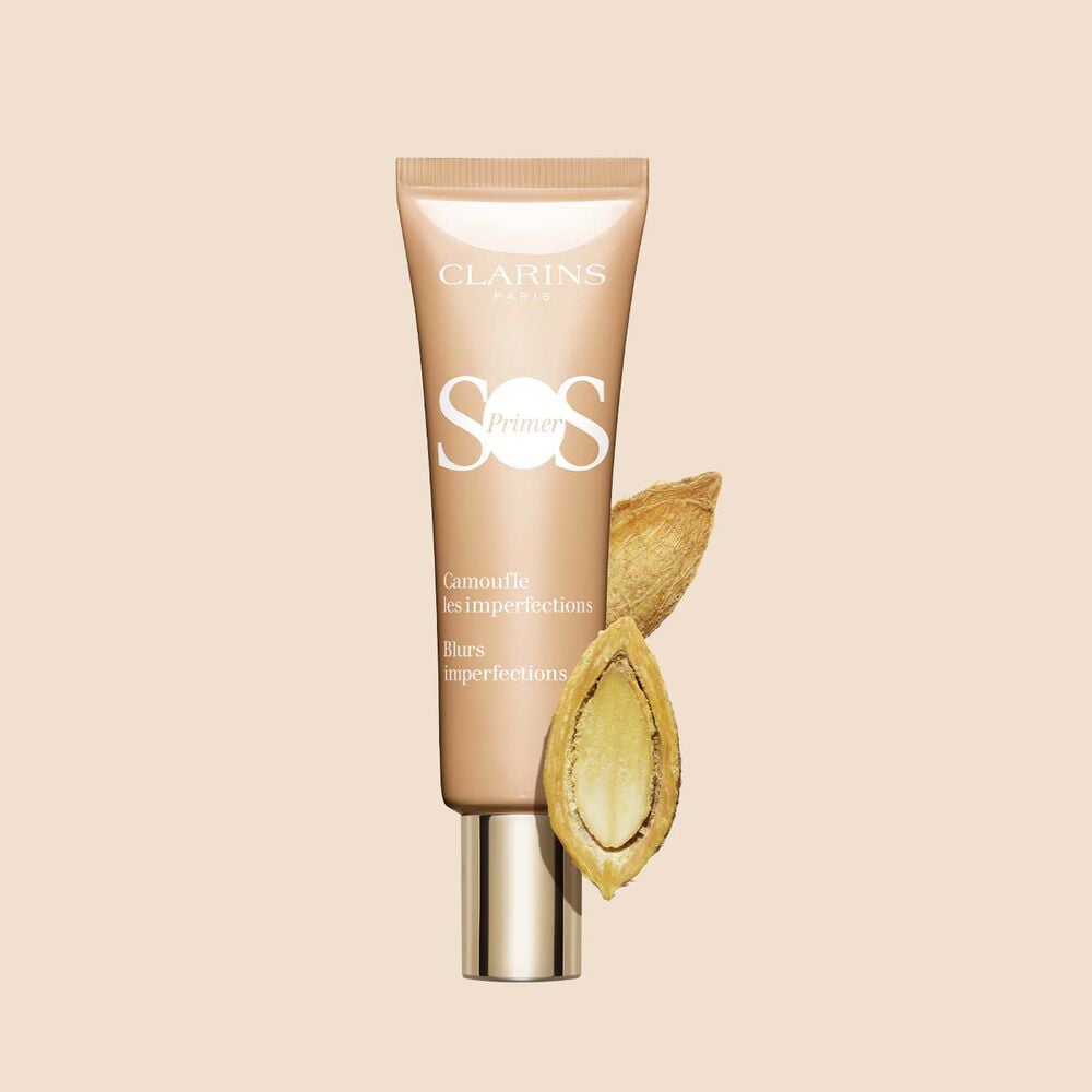 A tube of SOS Primer Peach by Clarins, which blurs imperfections and evens skin tone, featuring a desert date.