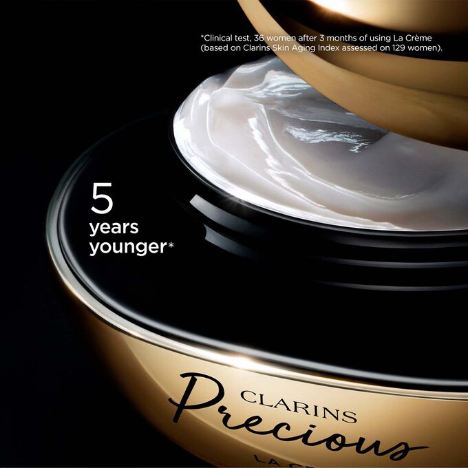 Packshot of Clarins Precious Soft Cream on dark background, with text emphasising its power to make skin appear 5 years younger.