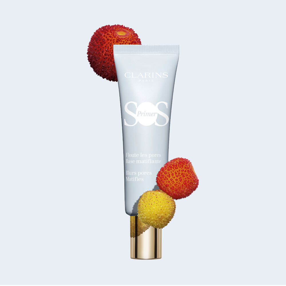 Tube of SOS Primer Mattifying by Clarins, which blurs pores and reduces shine, surrounded by strawberries and other fruits.
