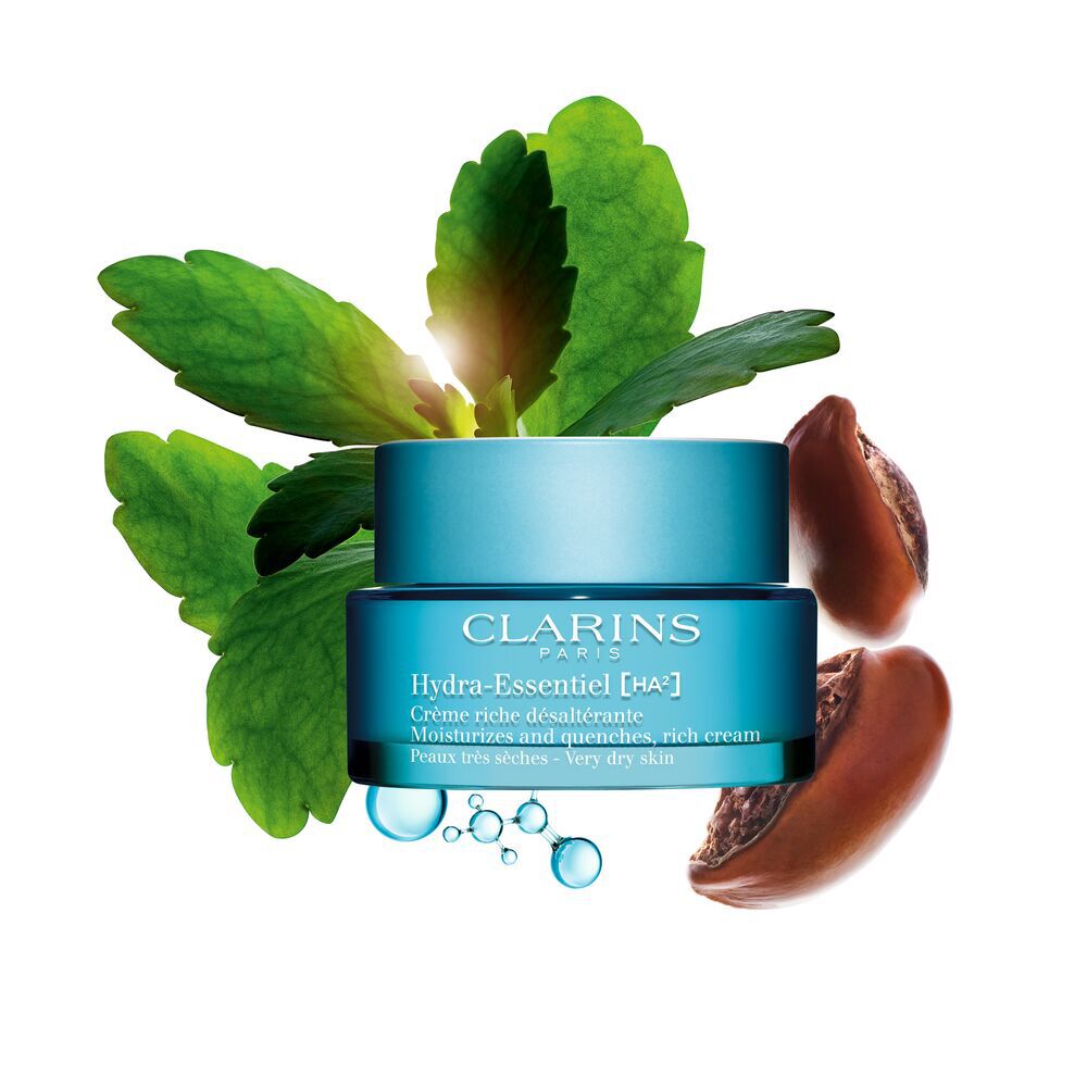 Packshot of Clarins Hydra-Essentiel Rich Cream close to some shea nuts and a kalanchoe leave on a blue background.