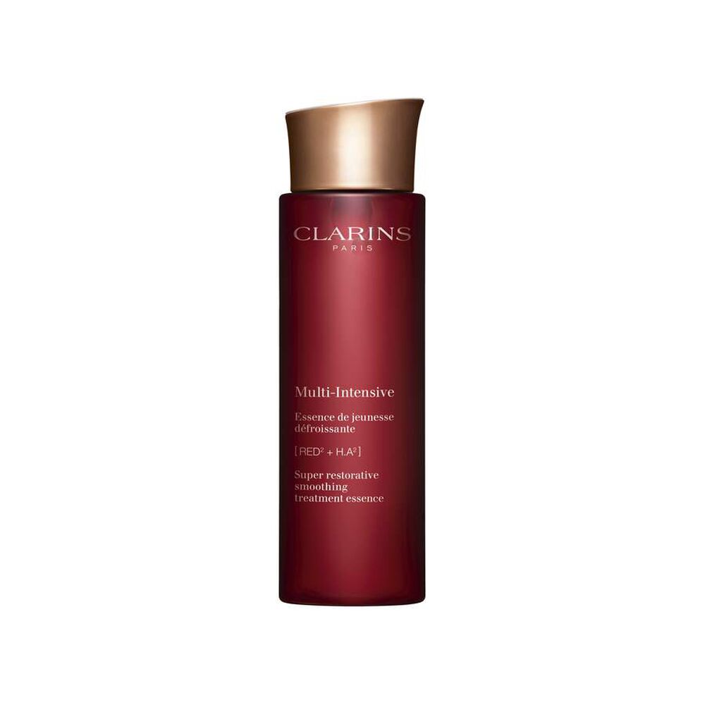 Packshot of Clarins Super Restorative Treatment Essence near red jania, Harungana leaves, and ginseng root on pink backdrop.