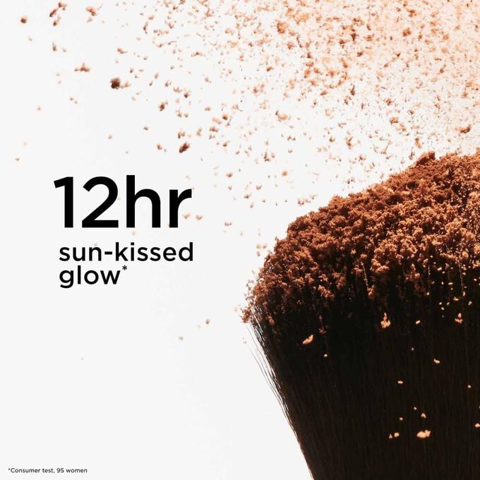 Focus on the top of a powder brush projecting bronzing powder, illustrating its 12-hour sun-kissed glow effect for a radiant finish.