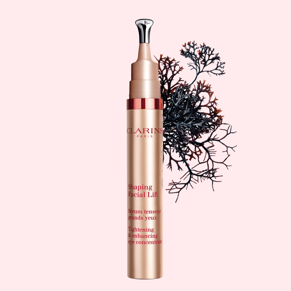 Packshot of a tube of the V Shaping Facial Lift Eye by Clarins close to Irish moss on a light pink background.