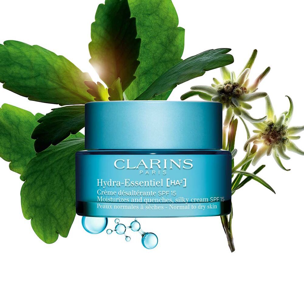 Packshot of Clarins Hydra-Essentiel SPF15 close to some edelweiss flowers on a blue background.