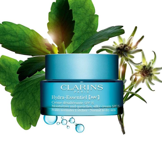 Packshot of Clarins Hydra-Essentiel SPF15 close to some edelweiss flowers on a blue background.