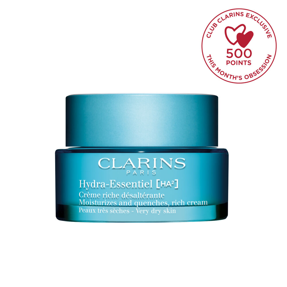 Packshot of Clarins Hydra-Essentiel Rich Cream close to some shea nuts and a kalanchoe leave on a blue background.