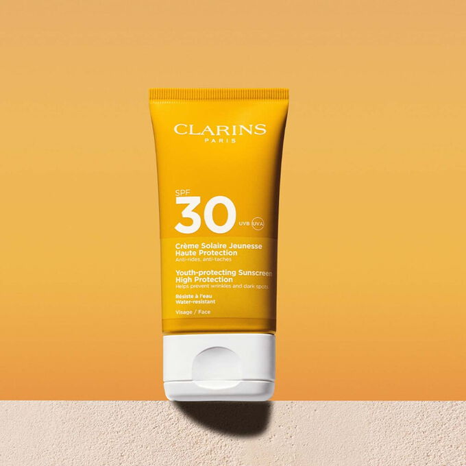 Packshot of a facial sun cream factor 30 tube with a message announcing that Clarins is committed to environmental protection